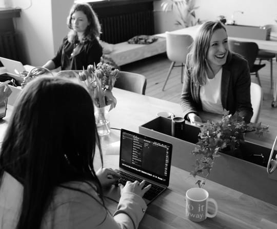 Group of women meeting around table with a purple hue over the photo